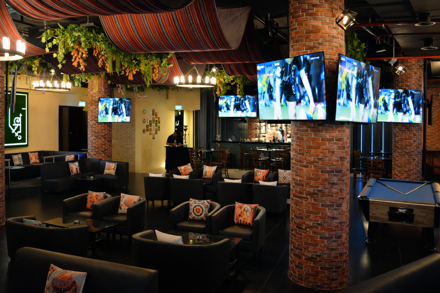 Guests watching live football match at Tiki Taka sports bar in Novotel Gate Abu Dhabi with indoor shisha and burgers